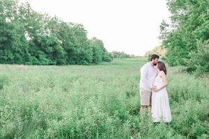 A dreamy outdoor family photoshoot in a lush green meadow with people wearing white attire.