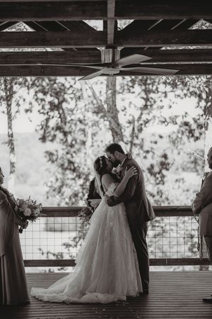 Black and white wedding portraits under a covered outdoor pavilion with natural backlighting.