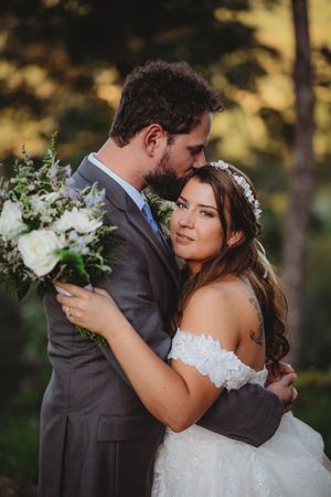 Romantic outdoor wedding portraits with golden sunlight filtering through trees in the background.