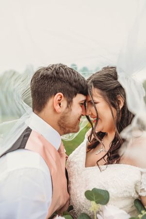 Romantic close-up portrait of newlyweds sharing an intimate moment under a veil.