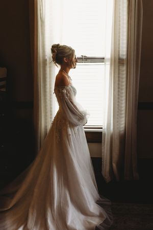 Artistic silhouette series of a bride in her wedding gown by a window.