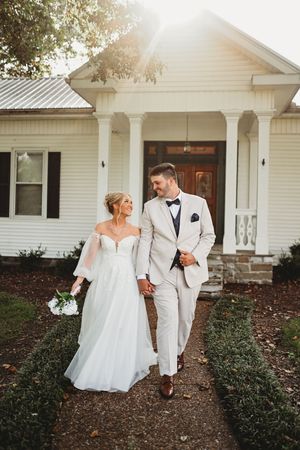 Wedding couple walking and posing outside a classic white farmhouse with columns.