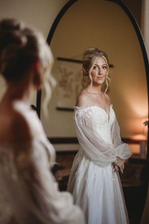 Elegant bridal portrait featuring a flowing white wedding gown with dramatic lighting and mirror reflections.