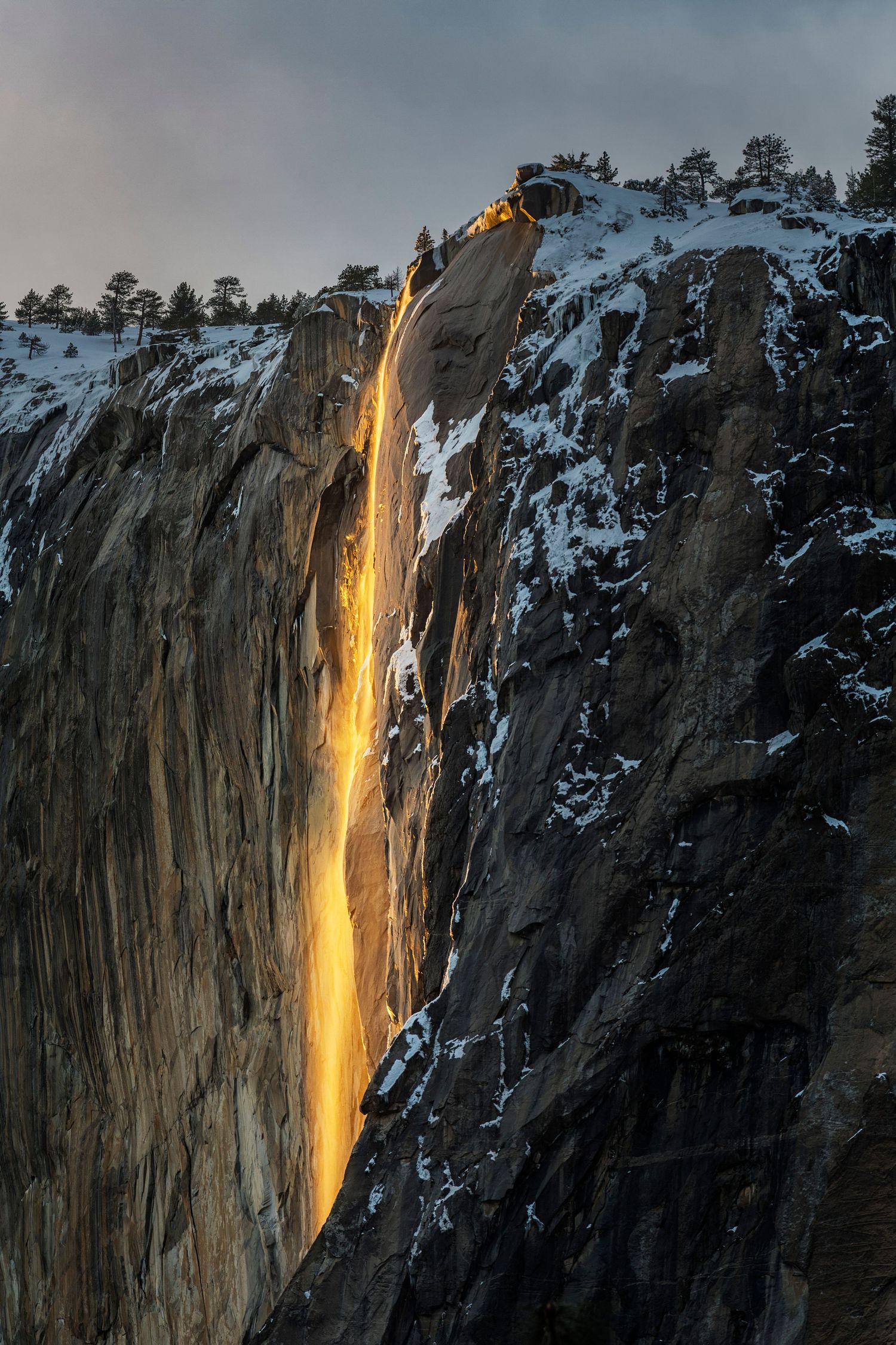 Horsetail Fall in Yosemite creates a glowing firefall effect at sunset as water cascades down the granite cliff face.