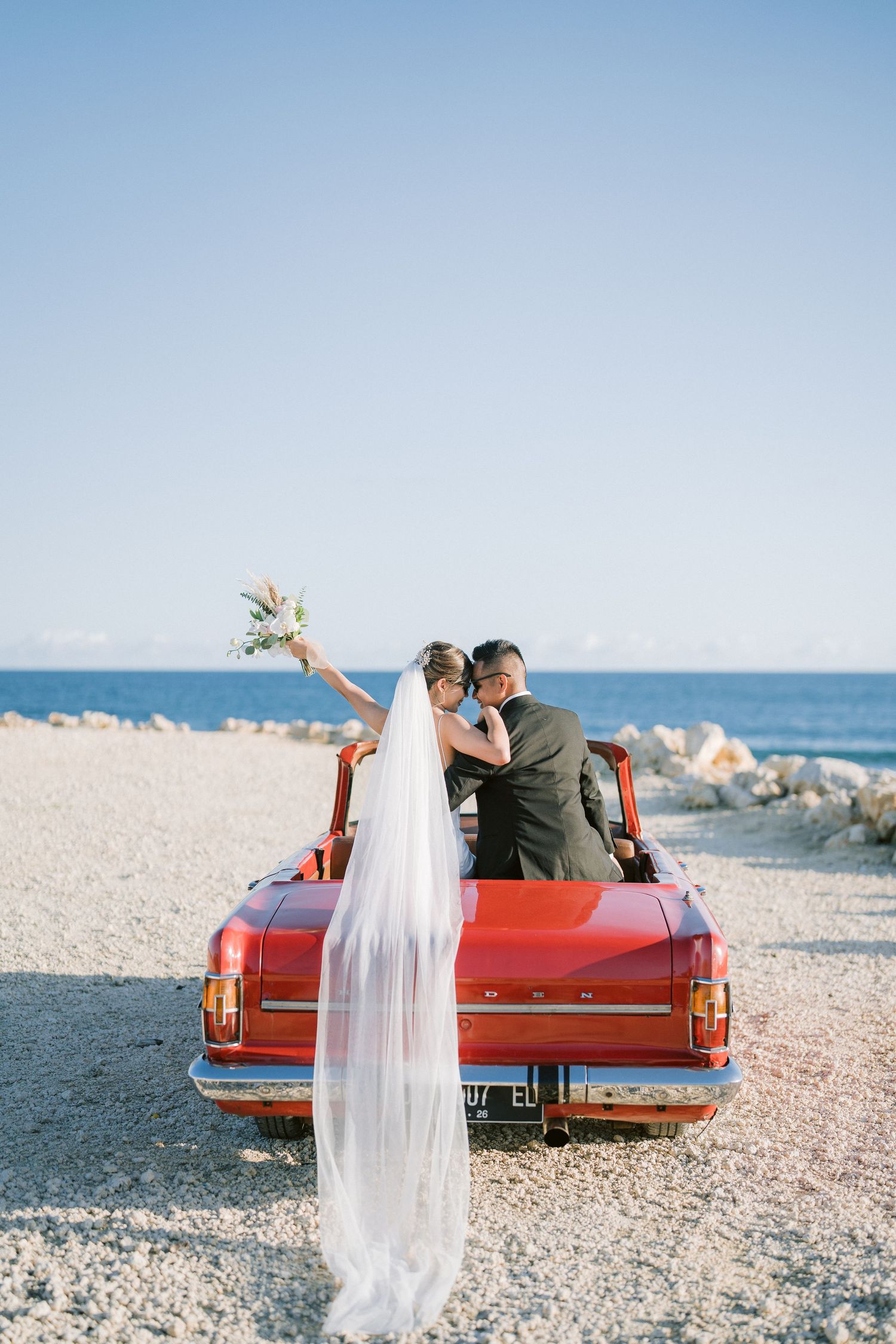 Bride and Groom pre-wedding photos with red car in Bali beach