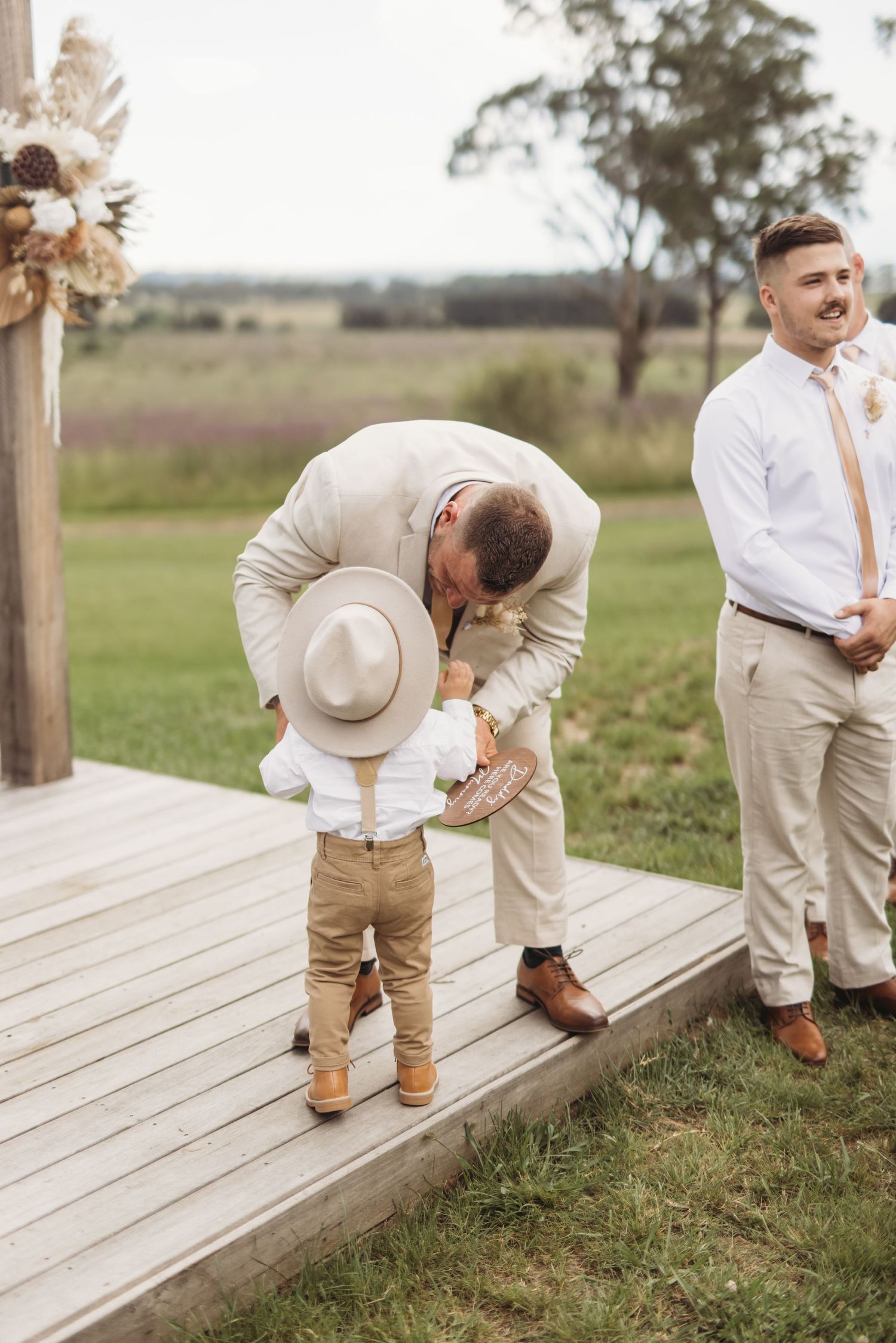 A heartwarming moment on a wooden deck during a rustic outdoor wedding ceremony.