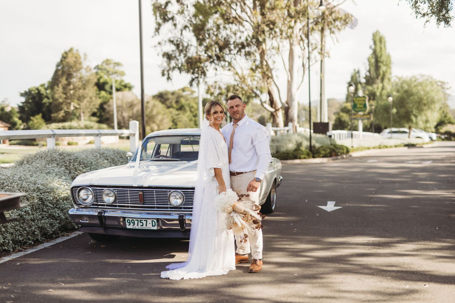A couple poses with their vintage car during their wedding photoshoot.