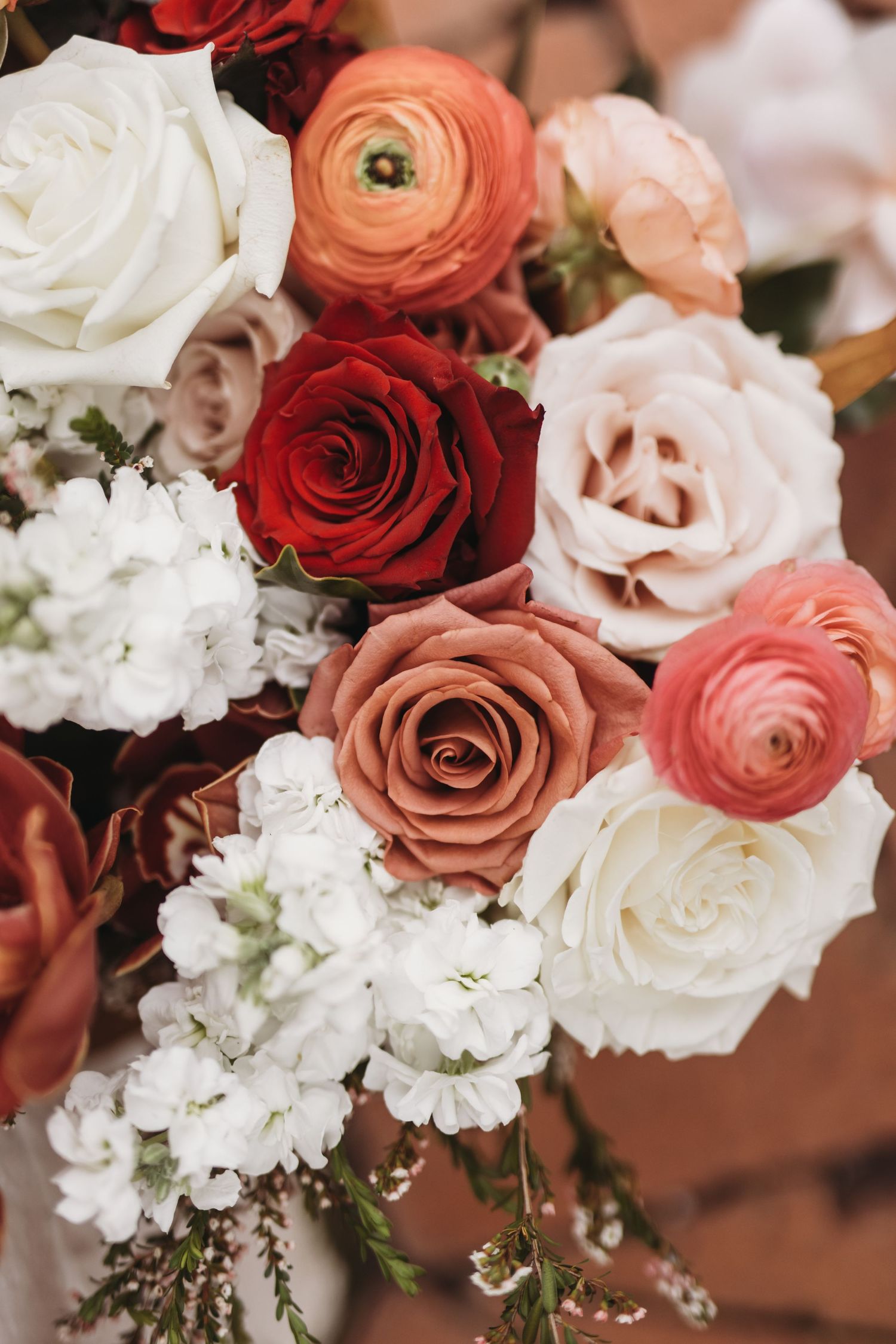 Close up of romantic wedding bouquet with white, red and peach roses mixed with white florals.