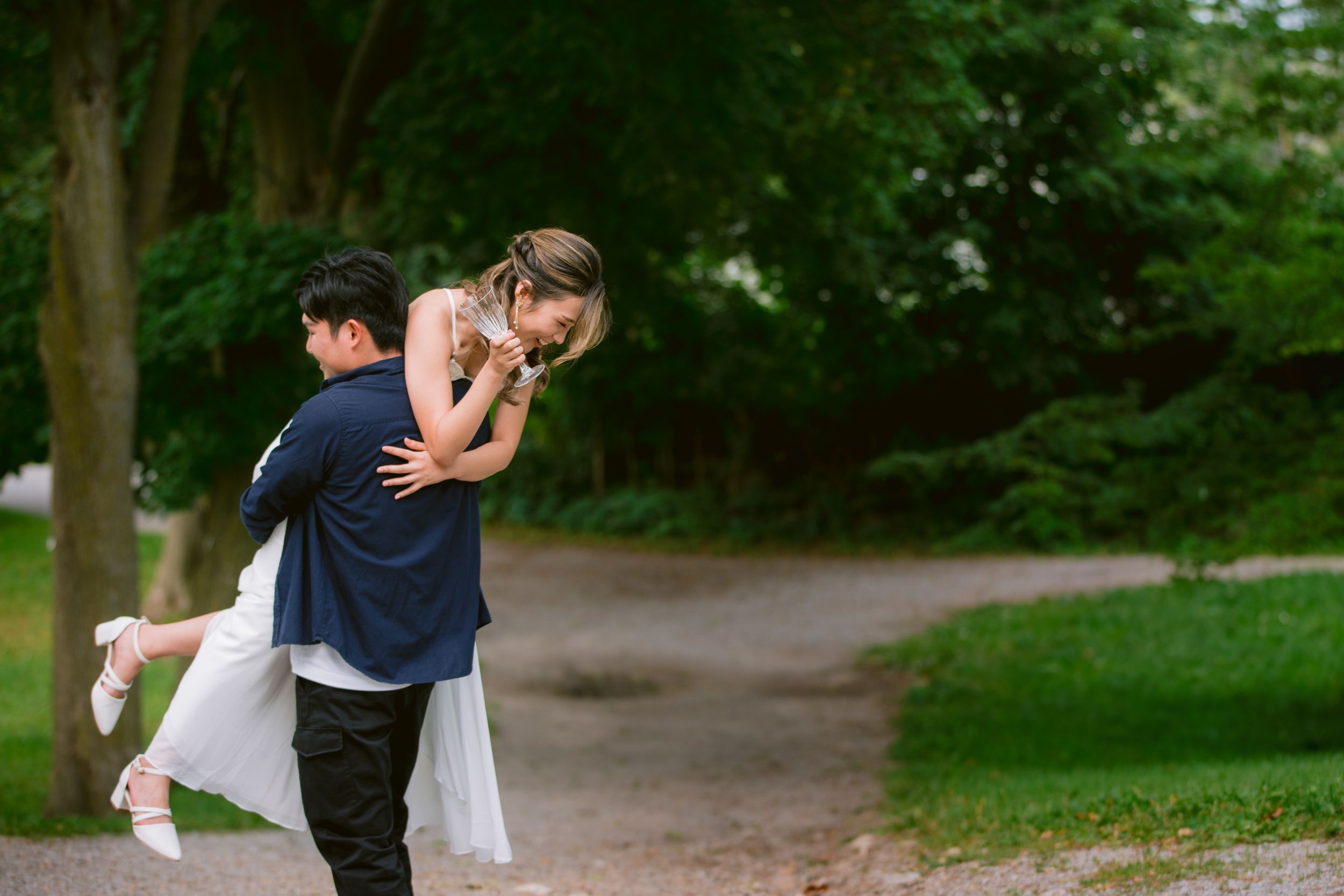 Romantic couple in wedding attire playfully posing in a park setting.