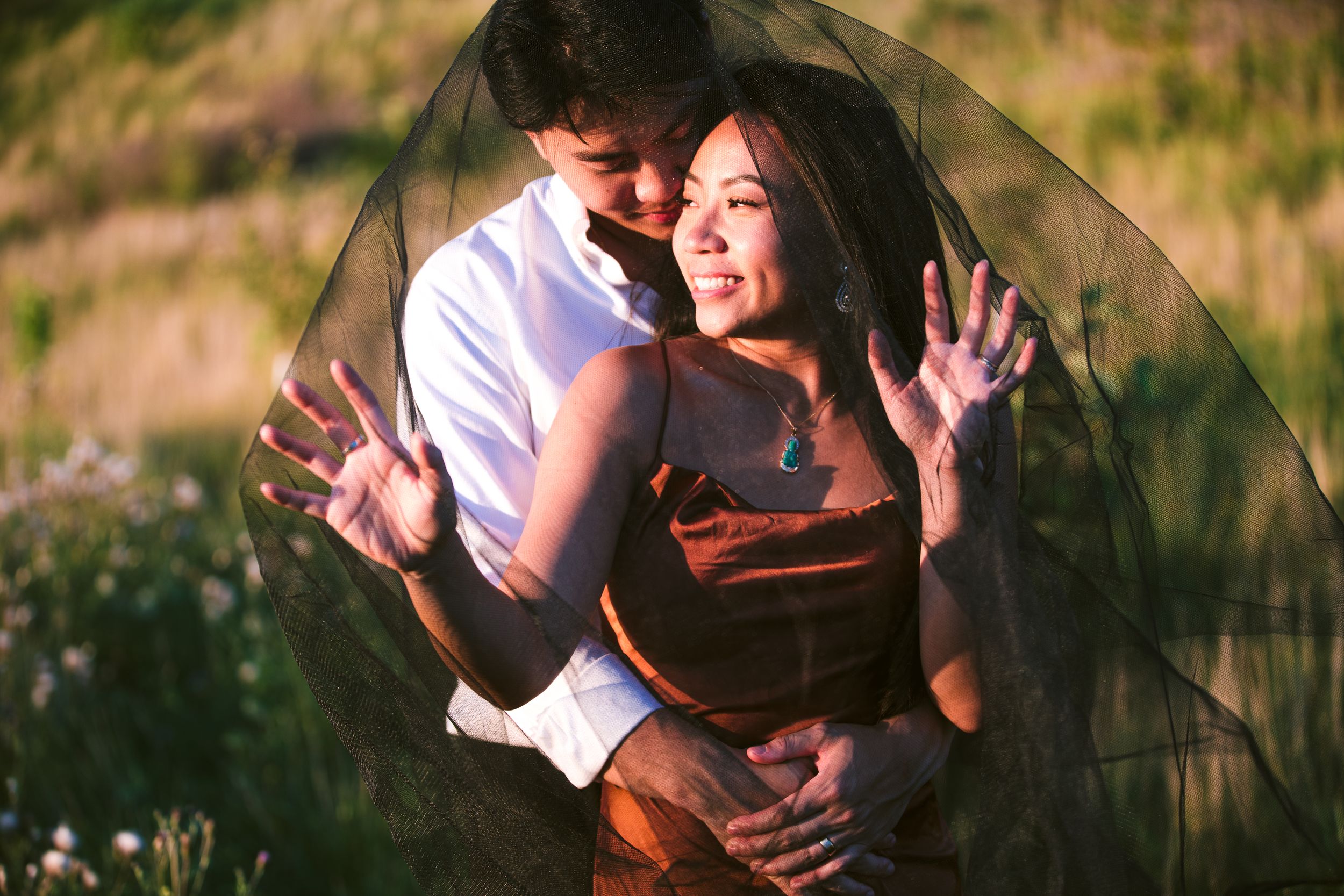 A joyful couple shares a playful moment in a summer field with natural lighting.