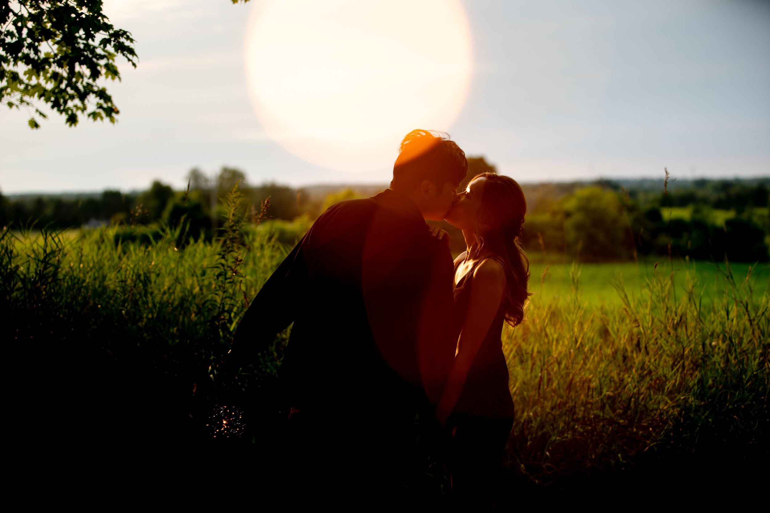 Silhouetted couple embracing at sunset in a golden-lit field.