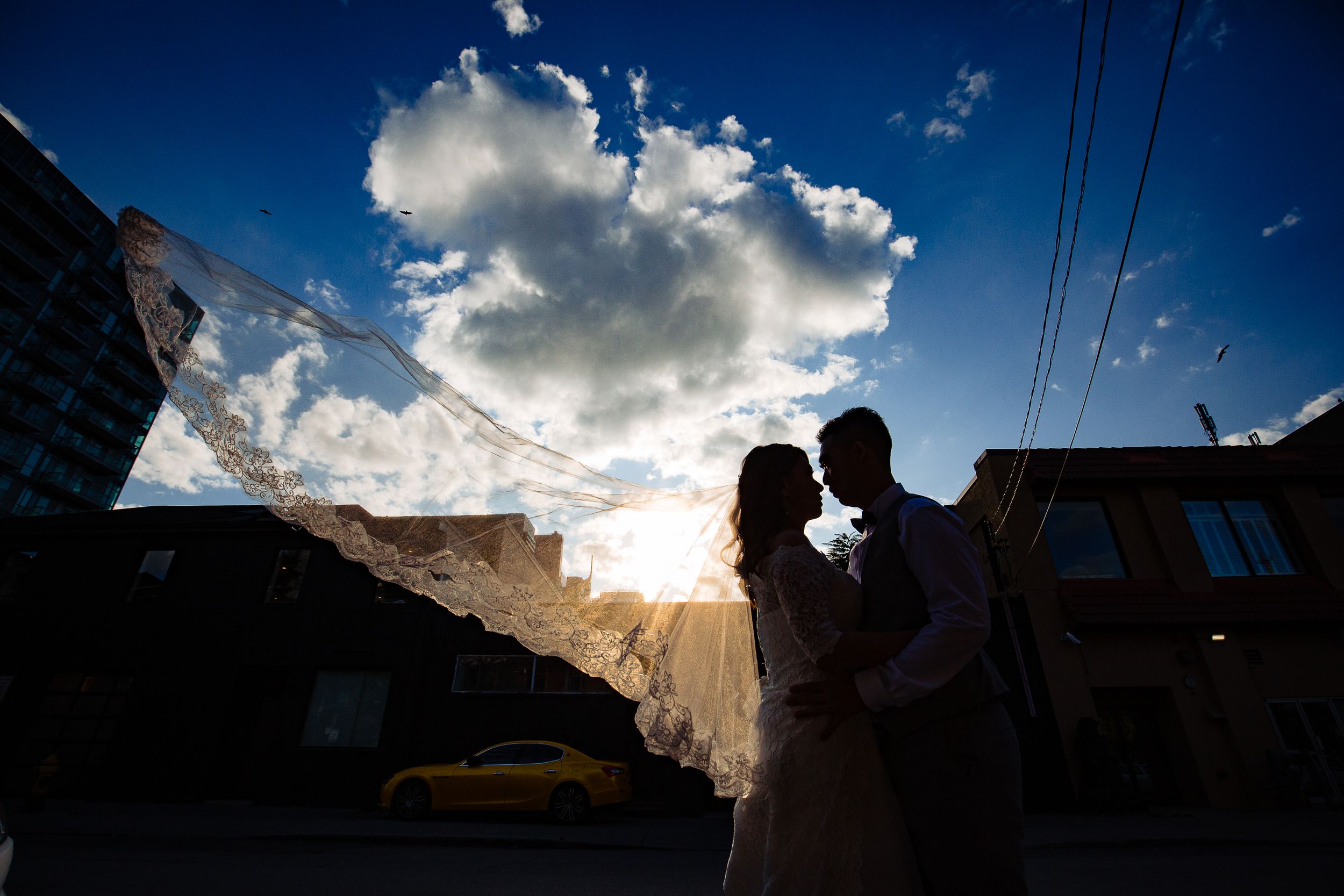 Romantic silhouette of couple against dramatic sunset sky with power lines.