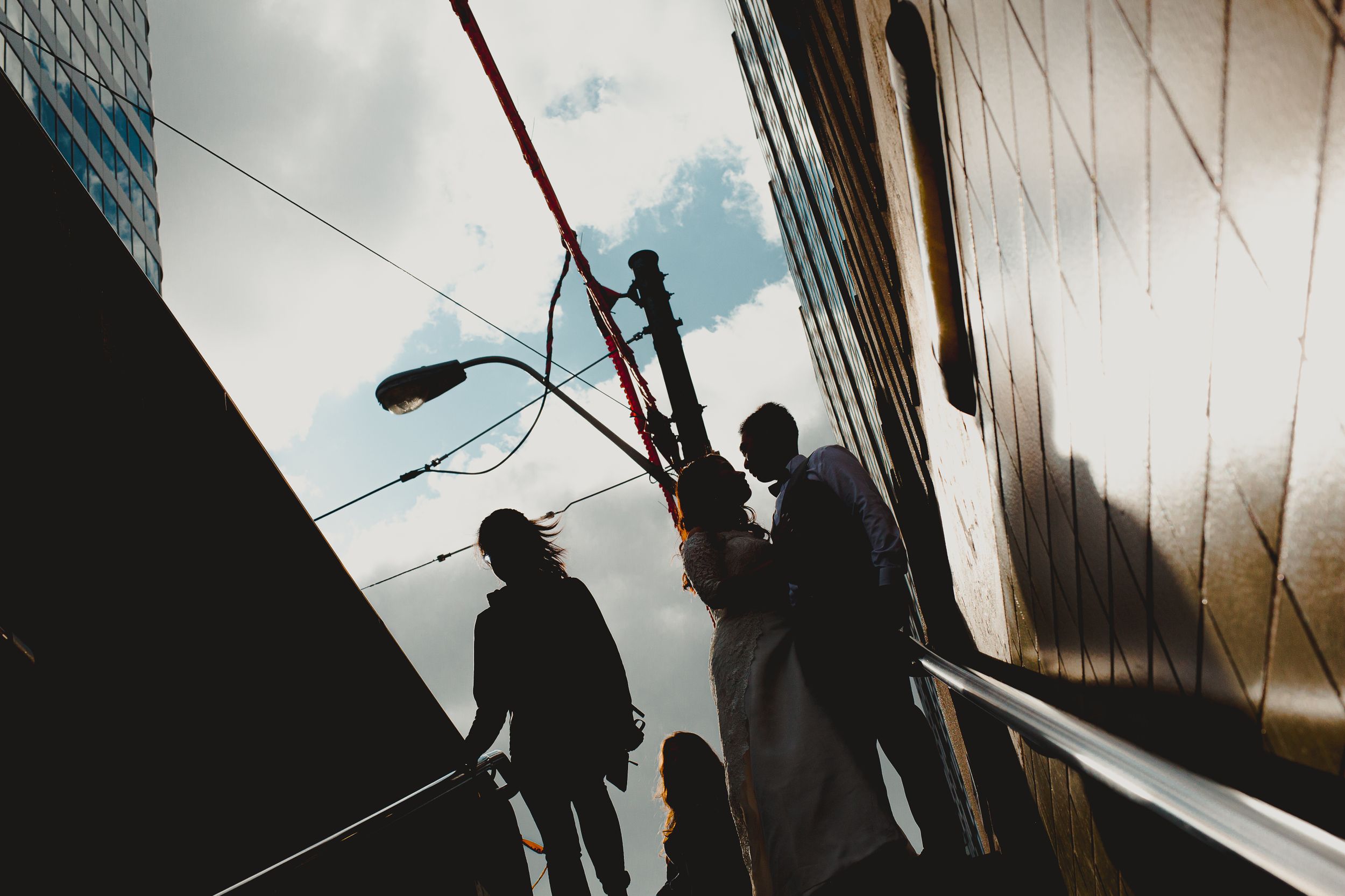 Silhouettes of people walking up stairs against geometric architectural shapes.
