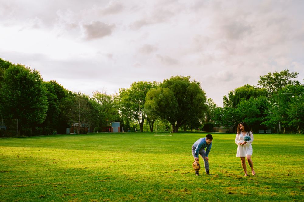A couple runs playfully through a green field during sunset.