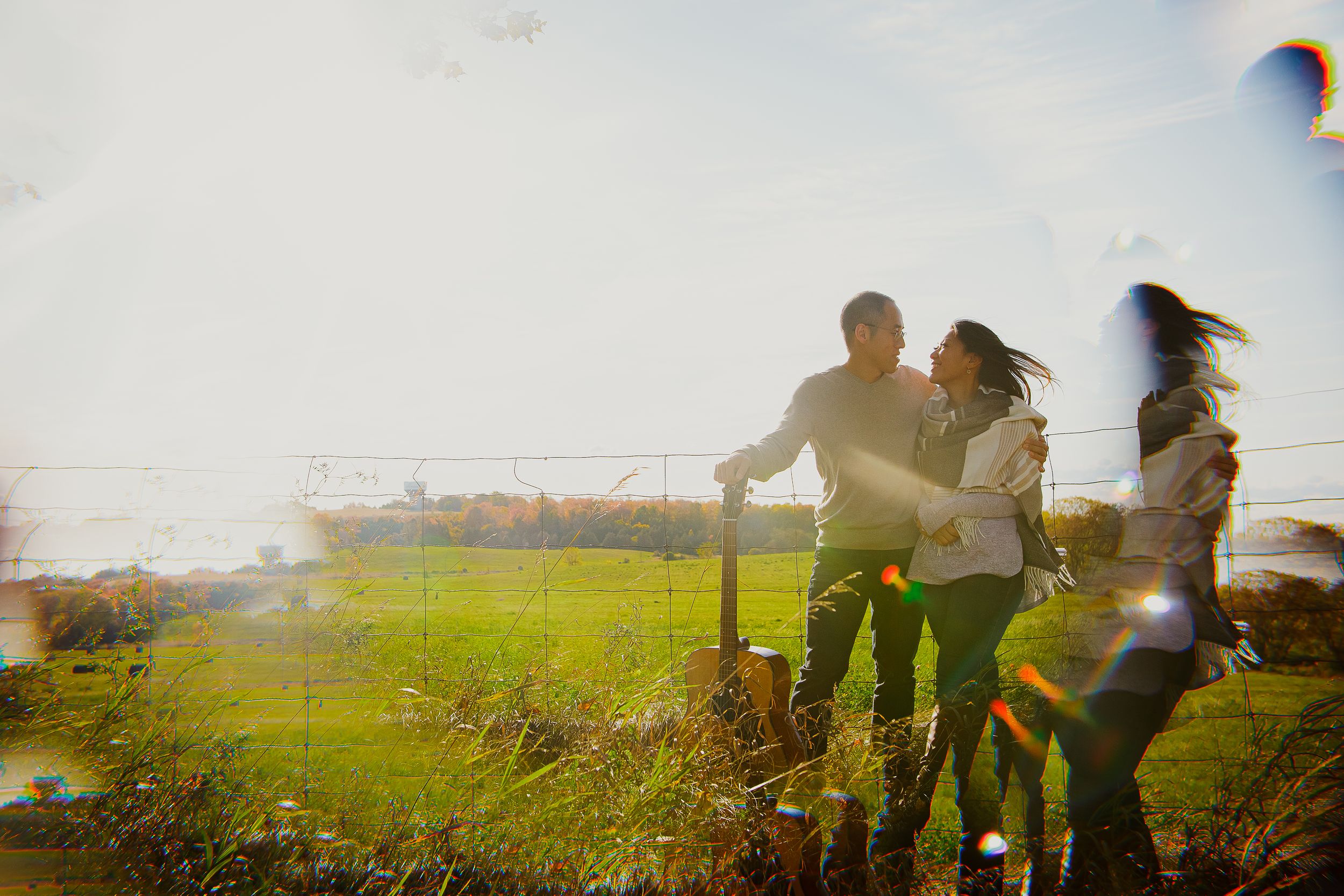 People enjoying a sunny day in a grassy field with lens flare effects.