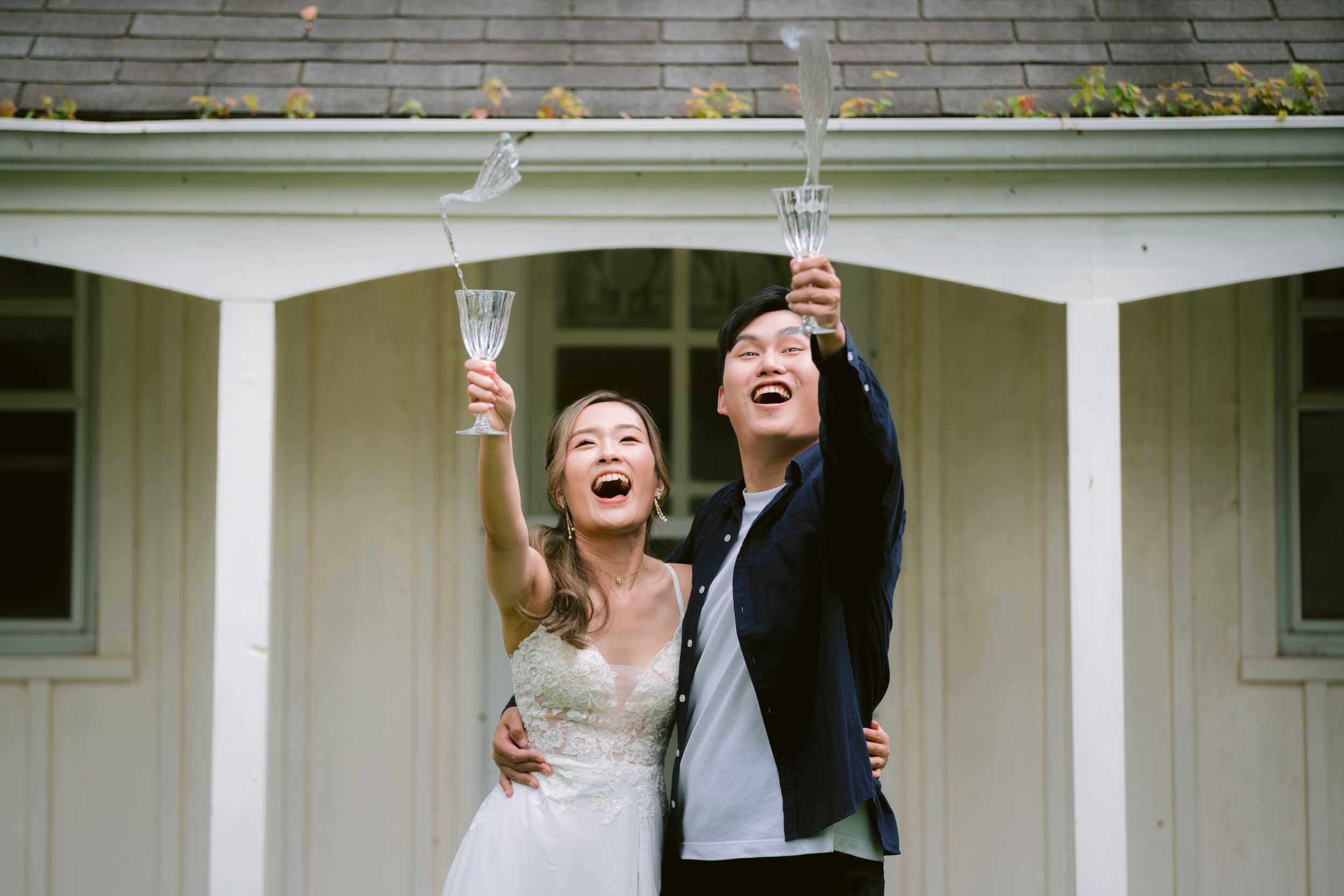Joyful newlyweds raising champagne glasses in celebration on their wedding day.