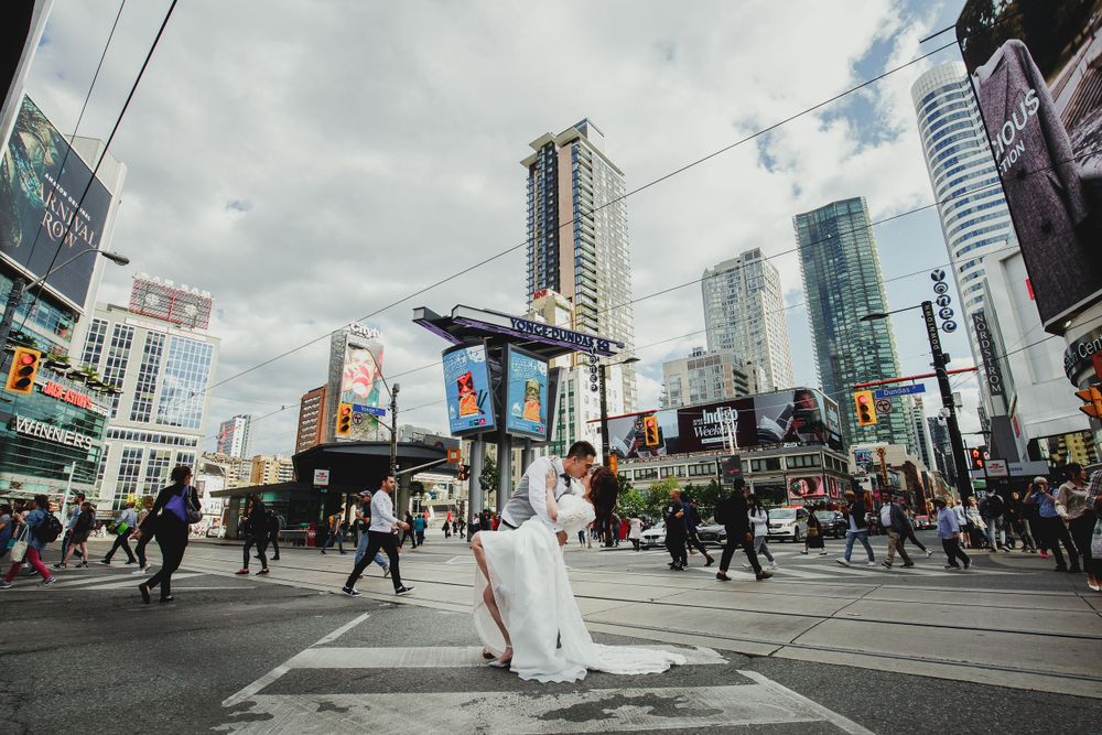 Wedding couple poses in busy downtown intersection surrounded by modern city buildings.