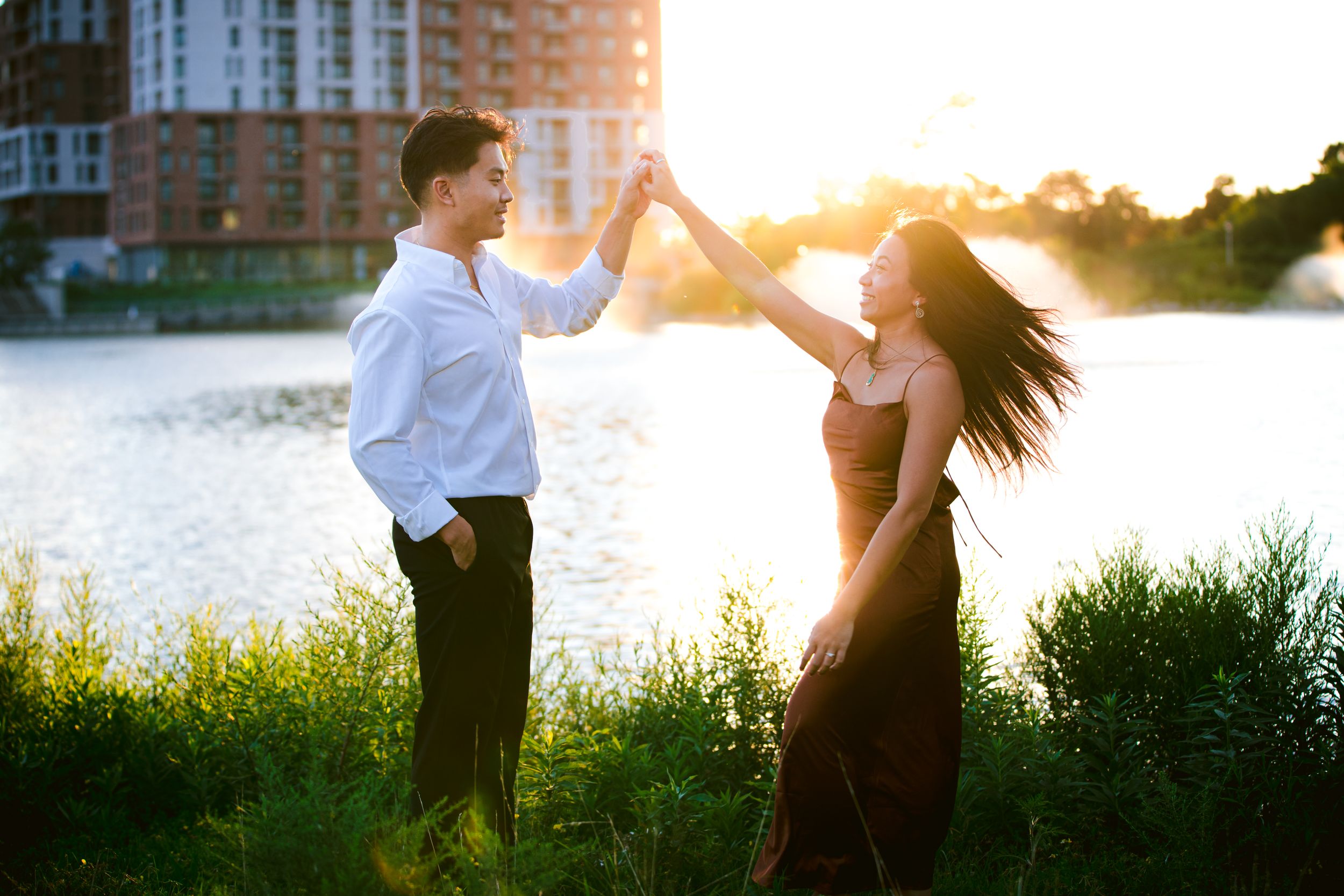 A couple dances together by the waterfront during a golden sunset.