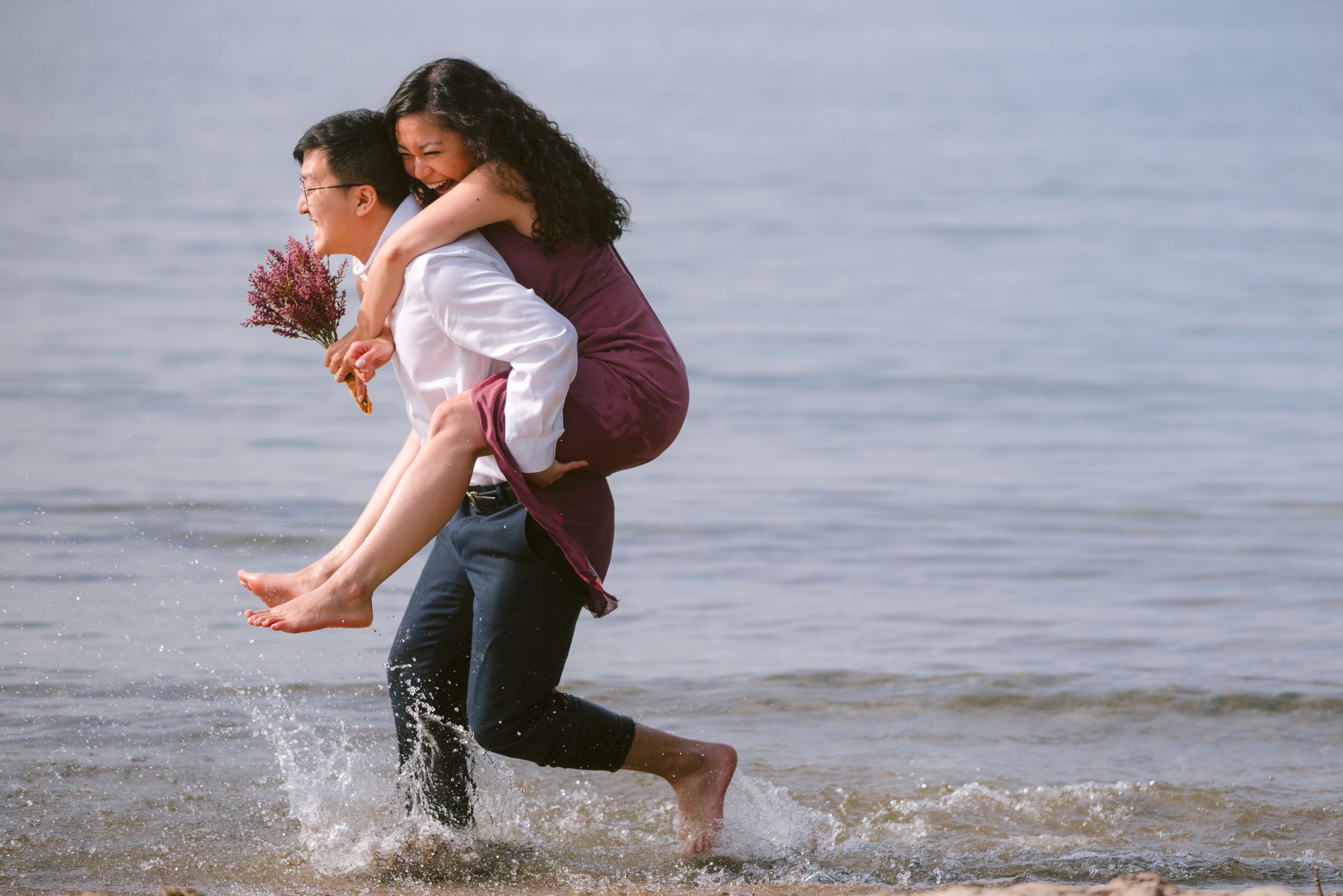 Playful couple running and splashing through ocean waves at the beach.