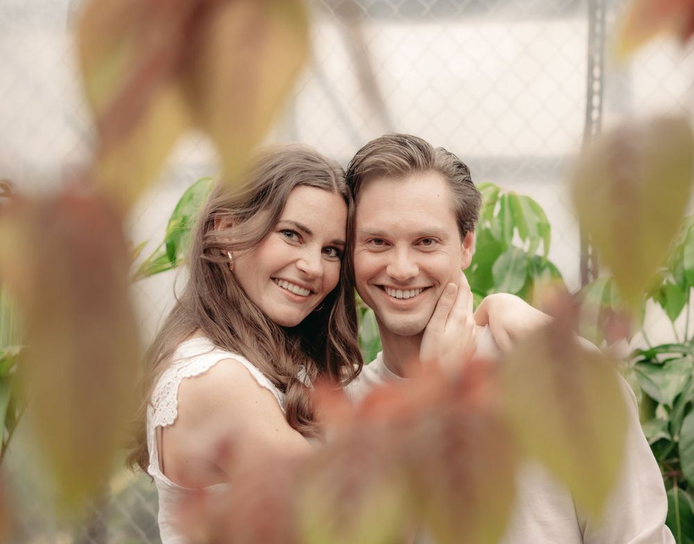 A romantic portrait captured in soft lighting with blurred foliage in the foreground.