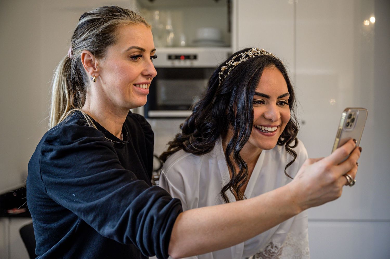 Bride looking at picture of the back of her hair with MUA