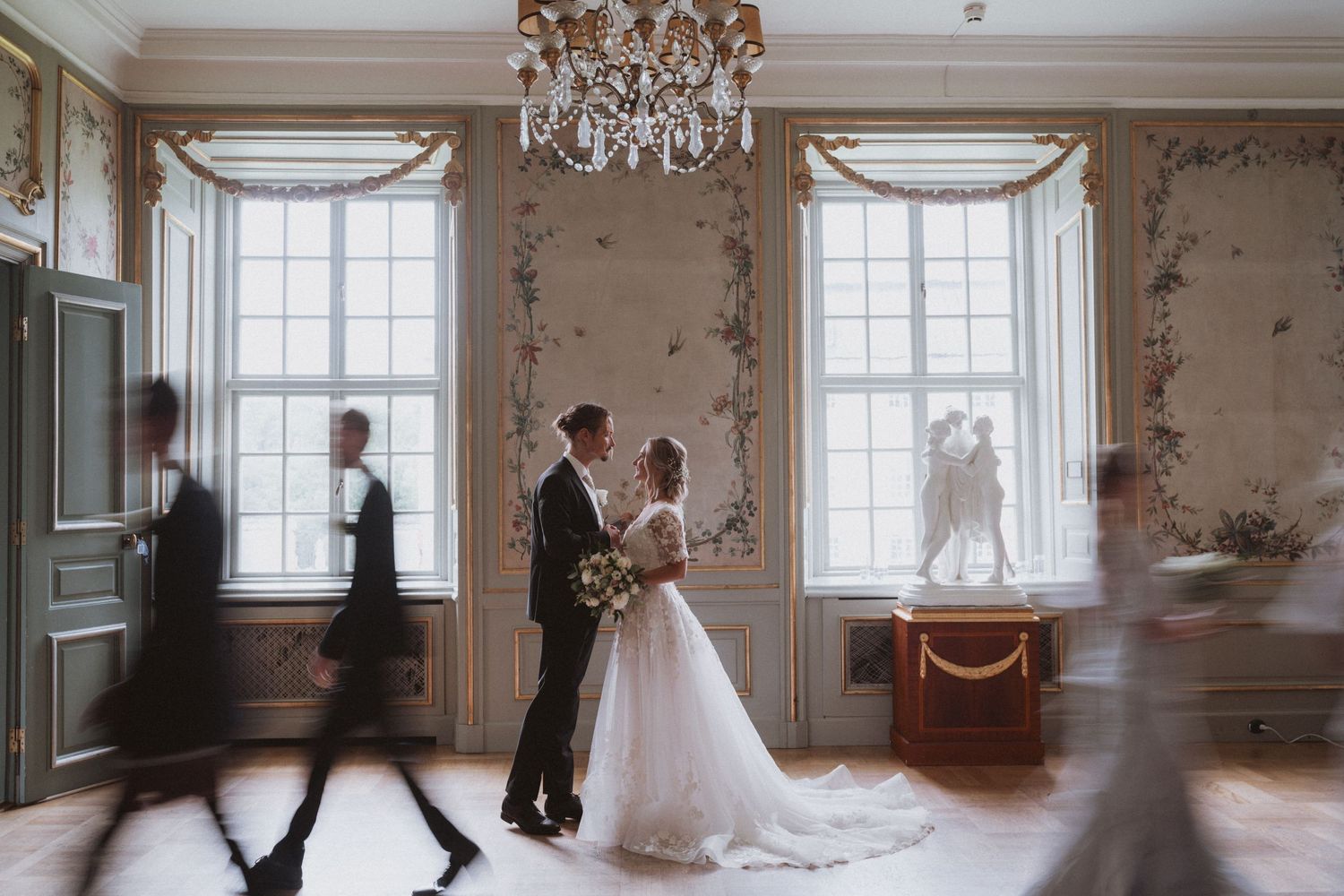 An elegant ballroom setting with crystal chandeliers and classic decor for a wedding.