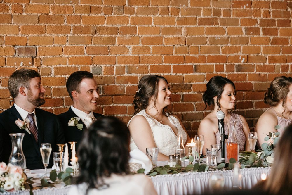 Bride and groom smiling at head table during wedding reception.