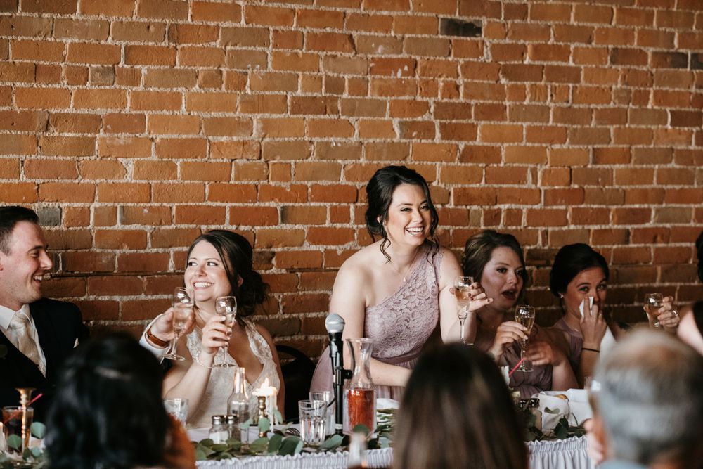 Bride and wedding party raising glasses for toast at reception.