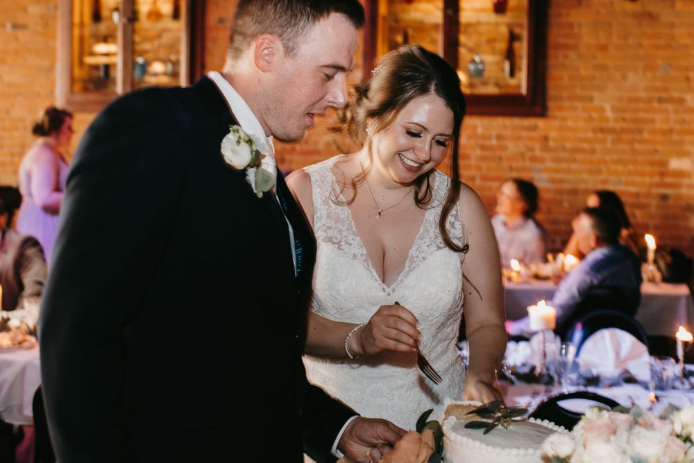 Happy bride and groom cutting their decorated wedding cake together at elegant reception.