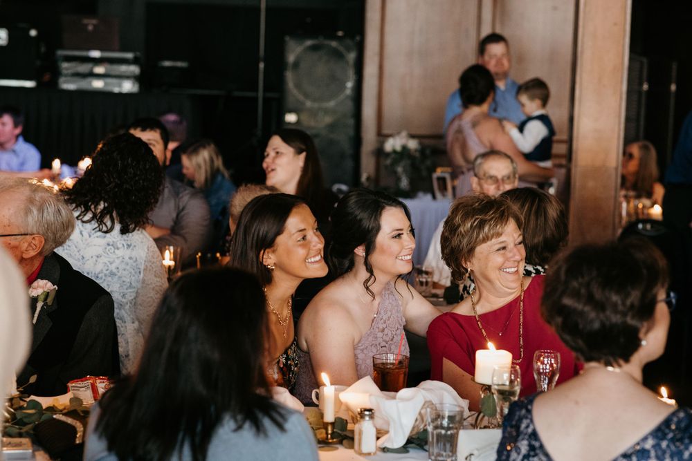 Wedding guests laughing and enjoying themselves at candlelit reception dinner tables.