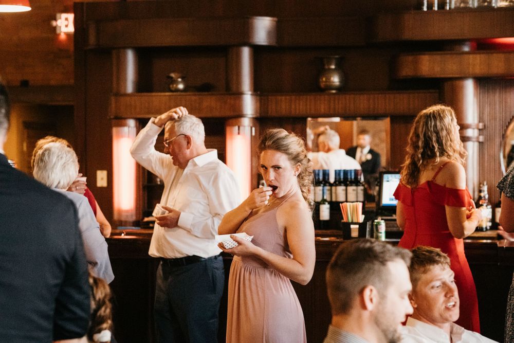 Wedding guests socializing and enjoying drinks at elegant wood-paneled reception bar.