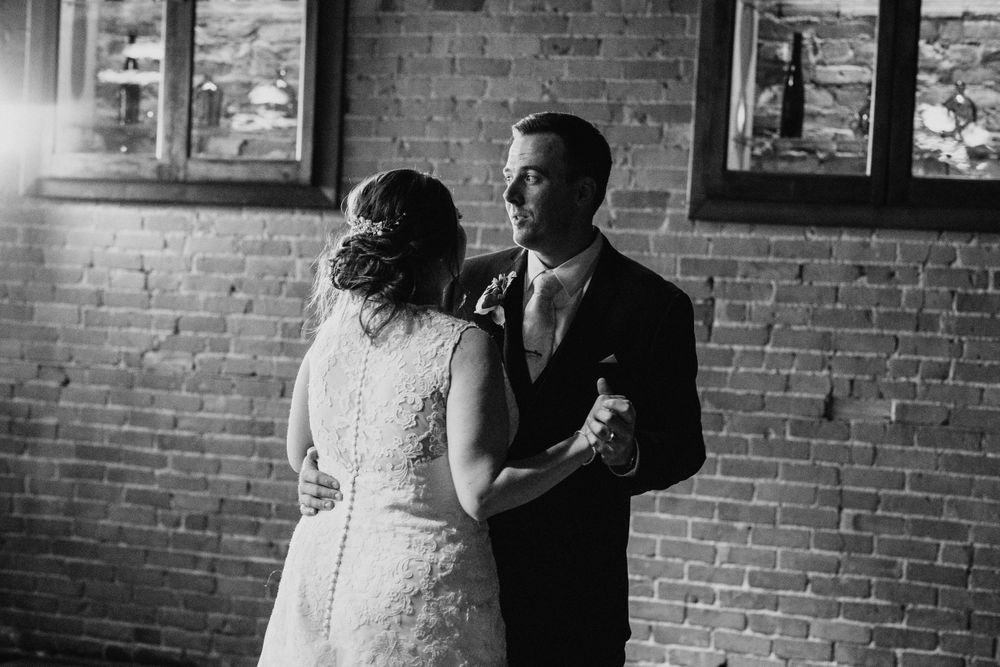 Black and white photo of bride and groom sharing their first dance at wedding reception.