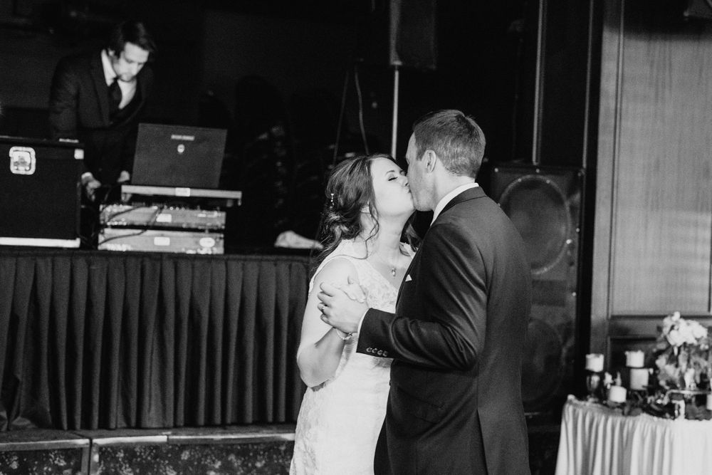 Bride and groom share a romantic kiss during their first dance at wedding reception.