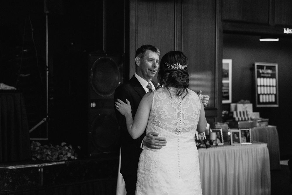 Black and white photo of bride and groom dancing together at elegant wedding reception.