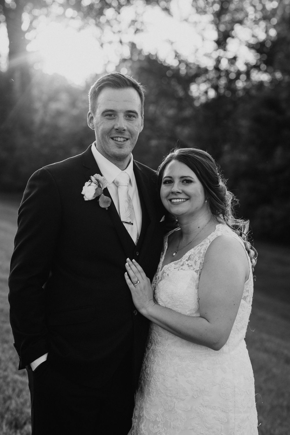 Black and white wedding portrait of smiling bride and groom during golden hour outdoors.