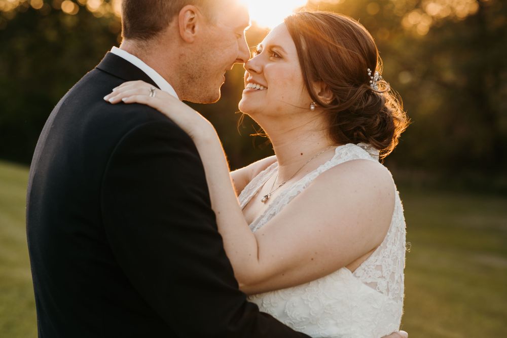 Close-up of bride smiling joyfully while embracing groom during warm golden hour sunset.