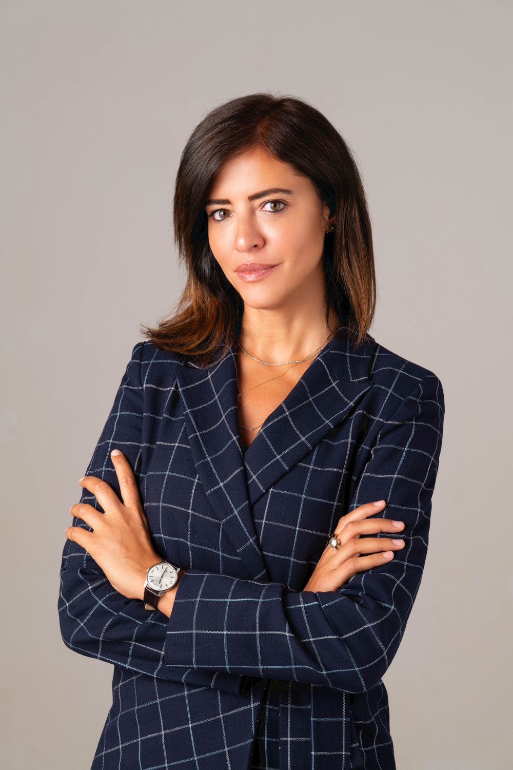 Professional woman in navy checkered blazer poses with crossed arms.