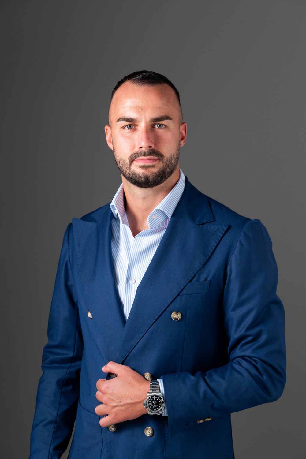 Professional portrait of executive in blue double-breasted suit with gold buttons.