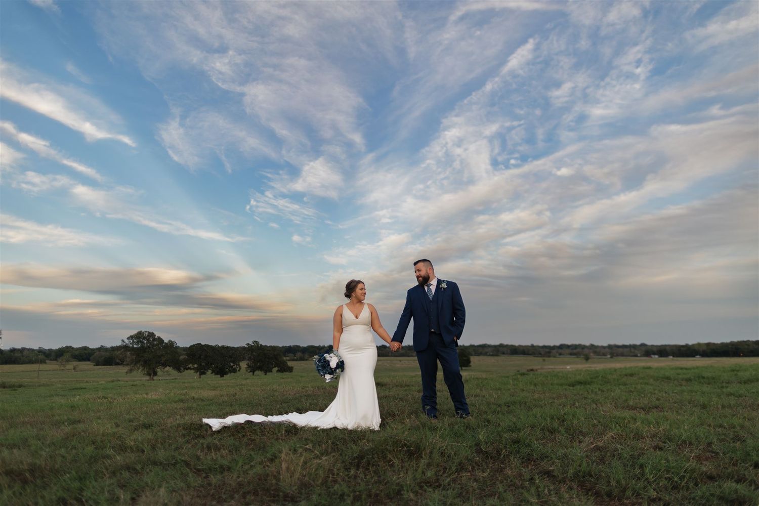 bride and groom standing together in pasture of the expansive property of Fannin Oaks