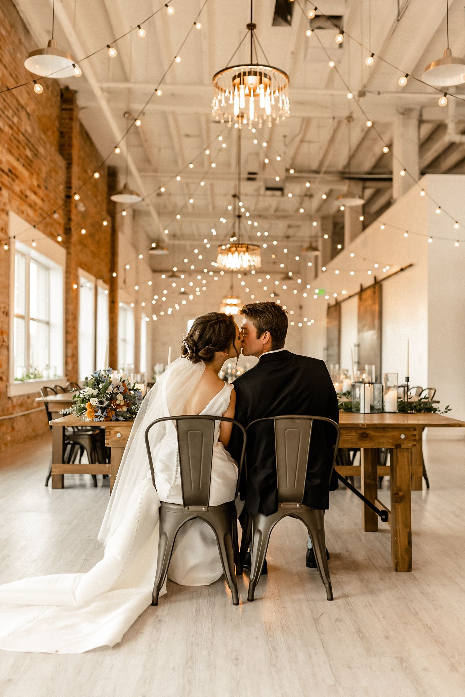 A wedding reception venue with string lights and chandeliers creating a romantic atmosphere.