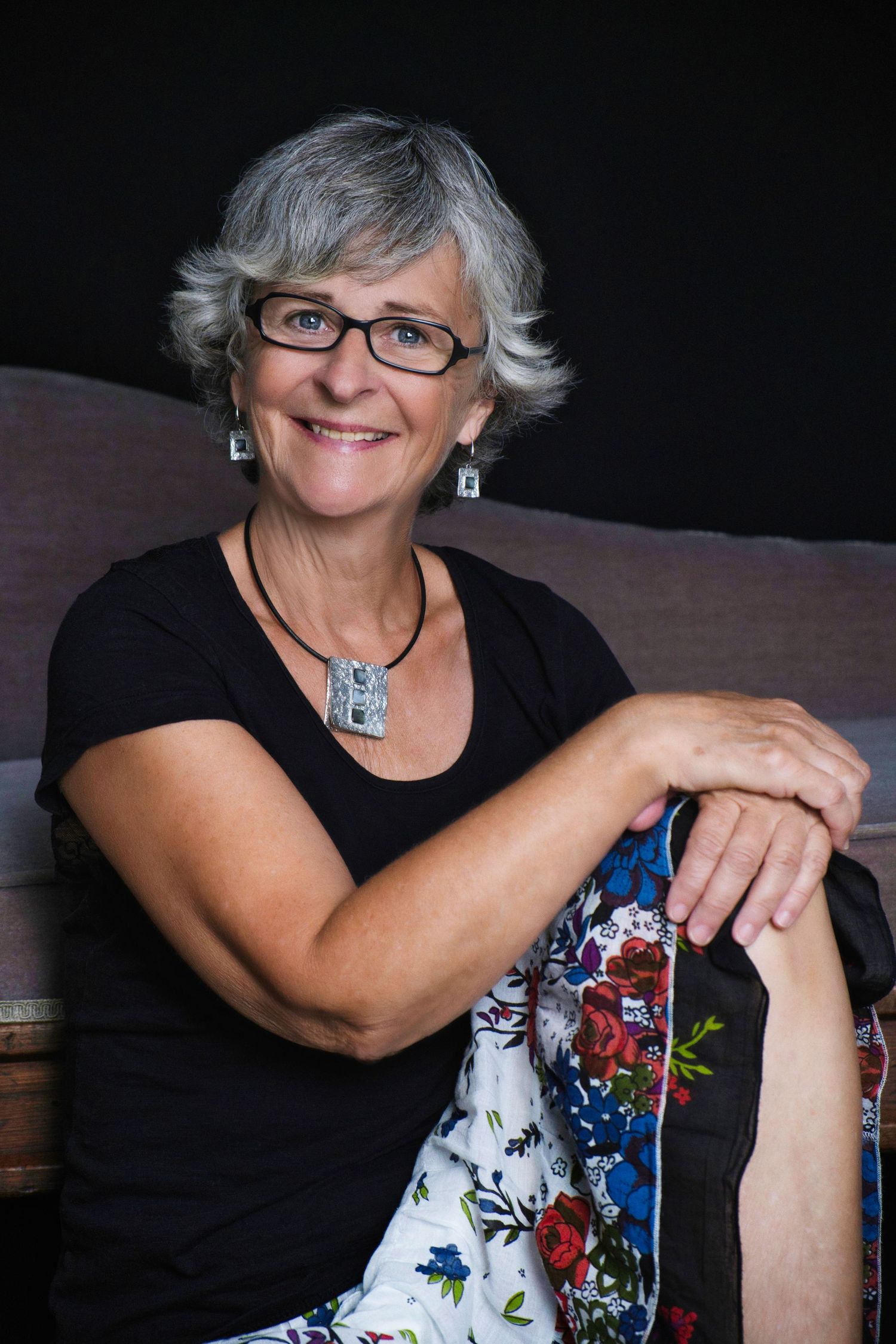 Portrait d'une femme souriante assise par terre.  Portrait of a woman sitting on the floor.