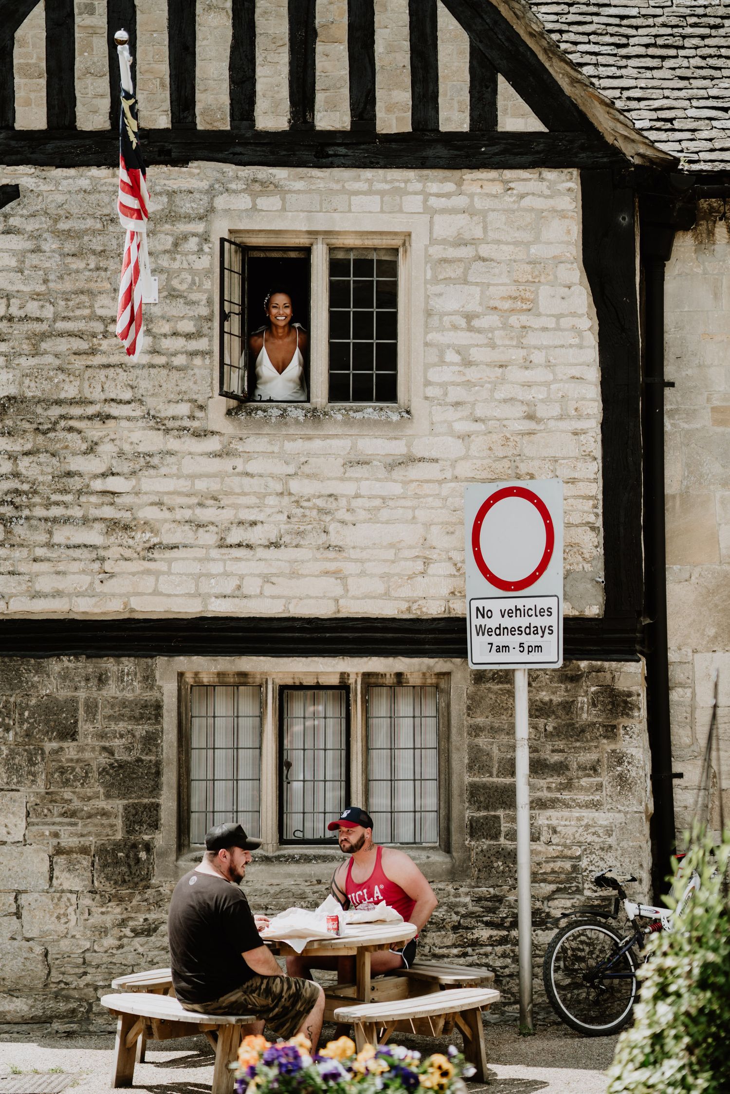 A charming scene with a window view and people dining at a rustic outdoor table.