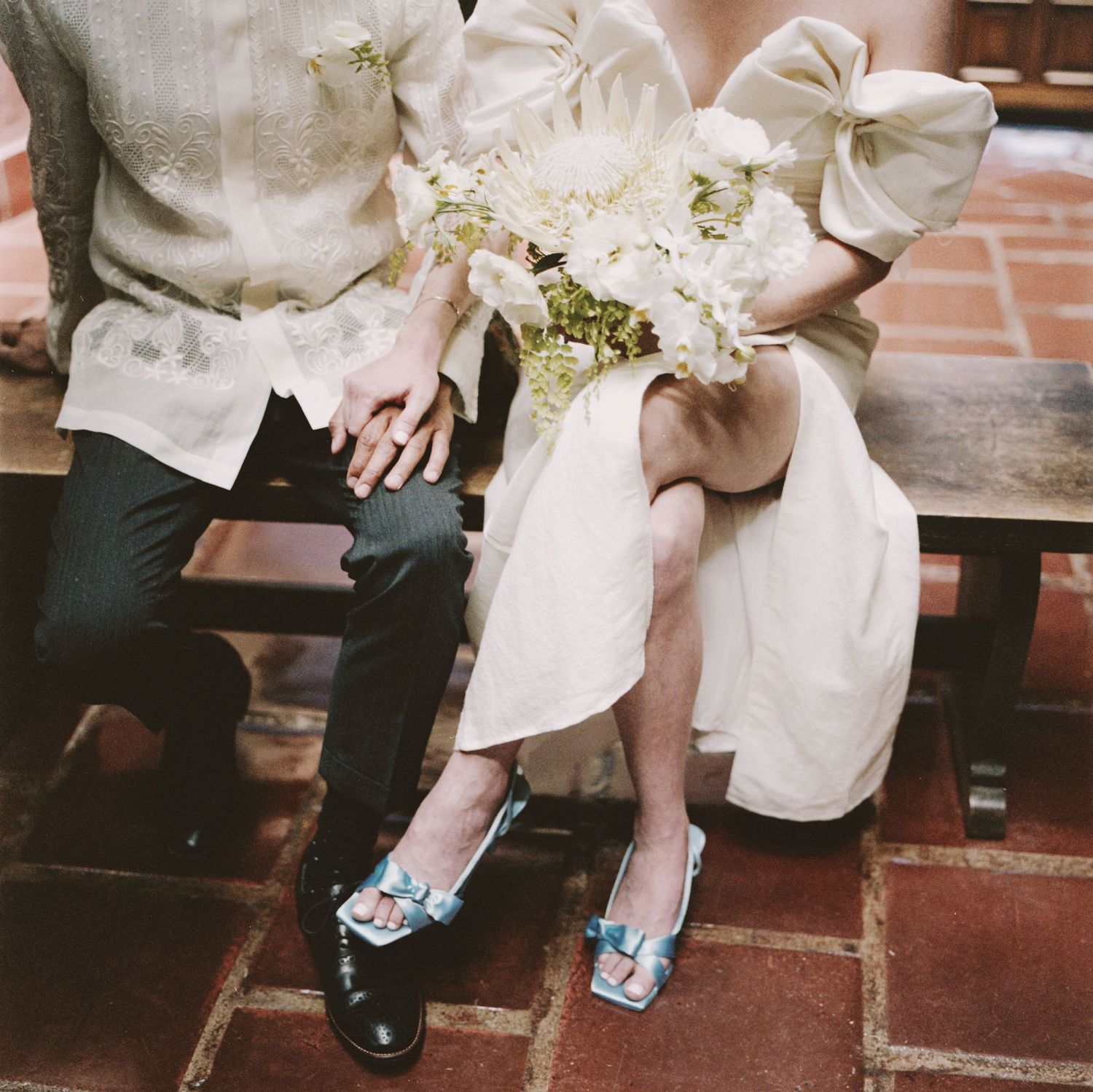 Close-up of wedding couple's legs showing ornate shoes and formal attire on tile steps.