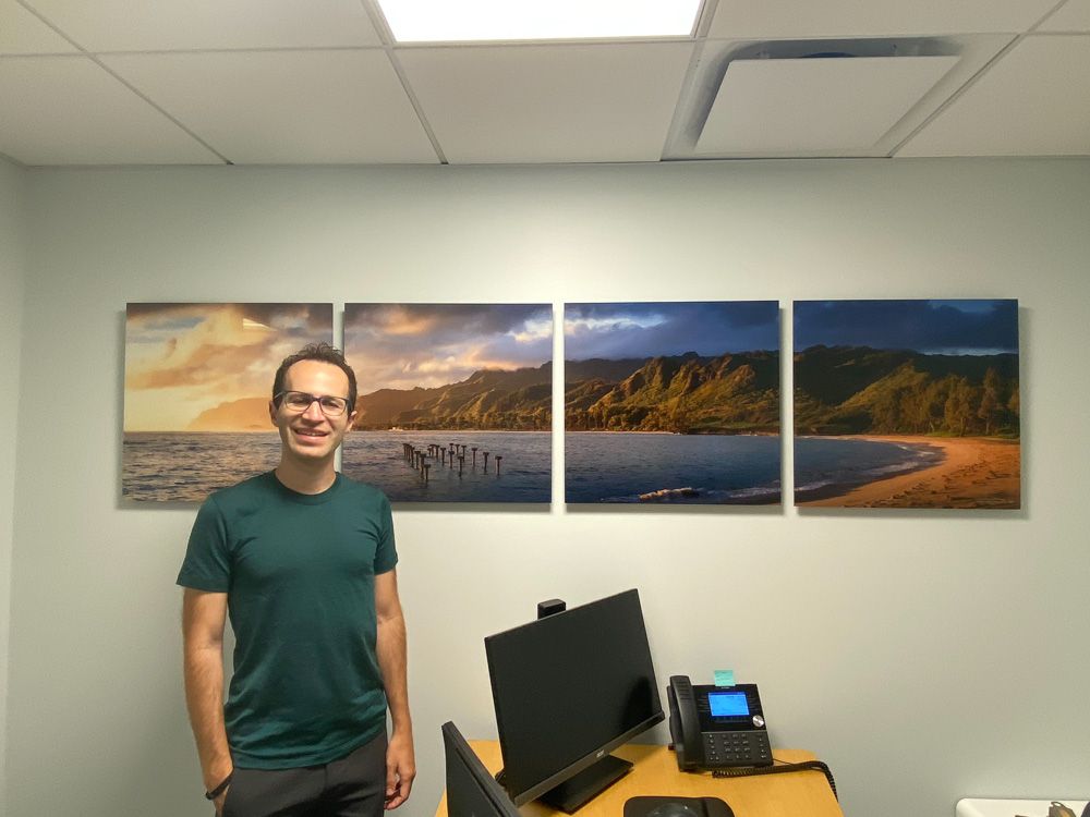 Office space decorated with three-panel coastal sunset artwork mounted on mint green wall.
