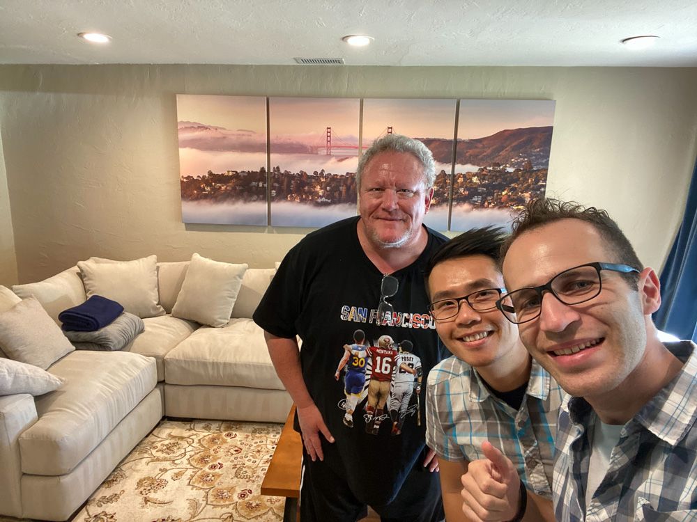 Group gathered in living room with mounted San Francisco cityscape artwork in background.