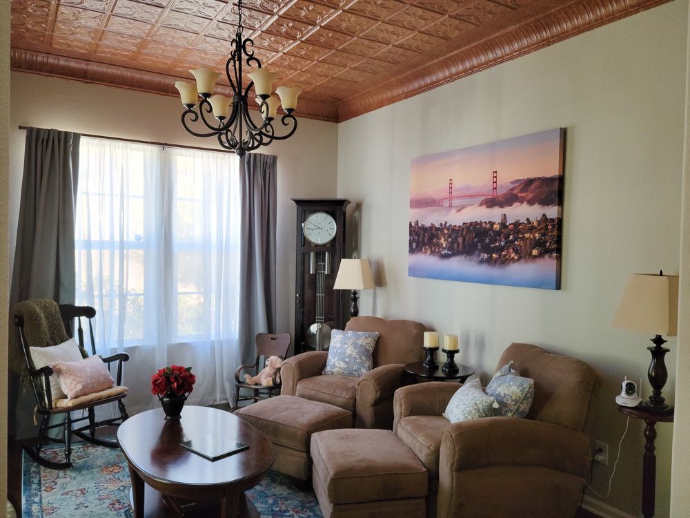 Cozy living room with copper ceiling, chandelier and scenic sunset artwork above brown recliners.