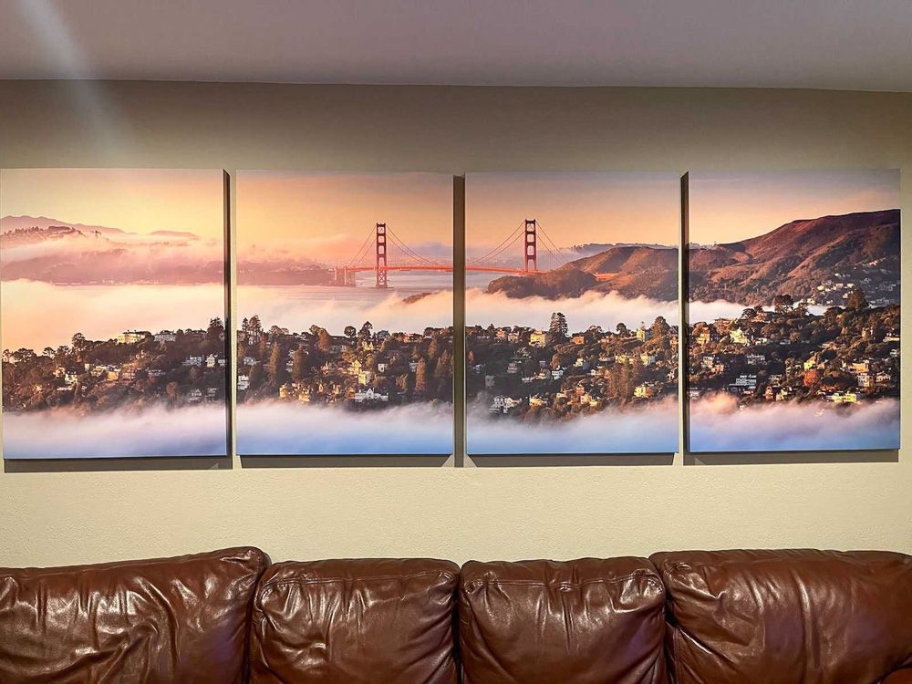 Four-panel Golden Gate Bridge artwork showing foggy San Francisco vista above leather couch.