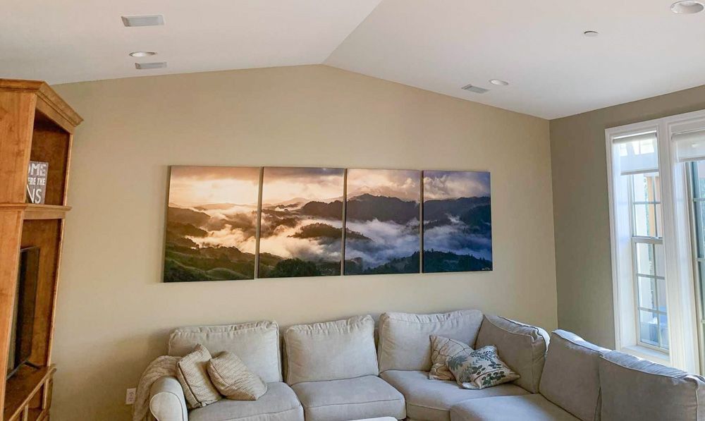 Elegant living room with multi-panel seascape artwork mounted above grey sectional sofa.