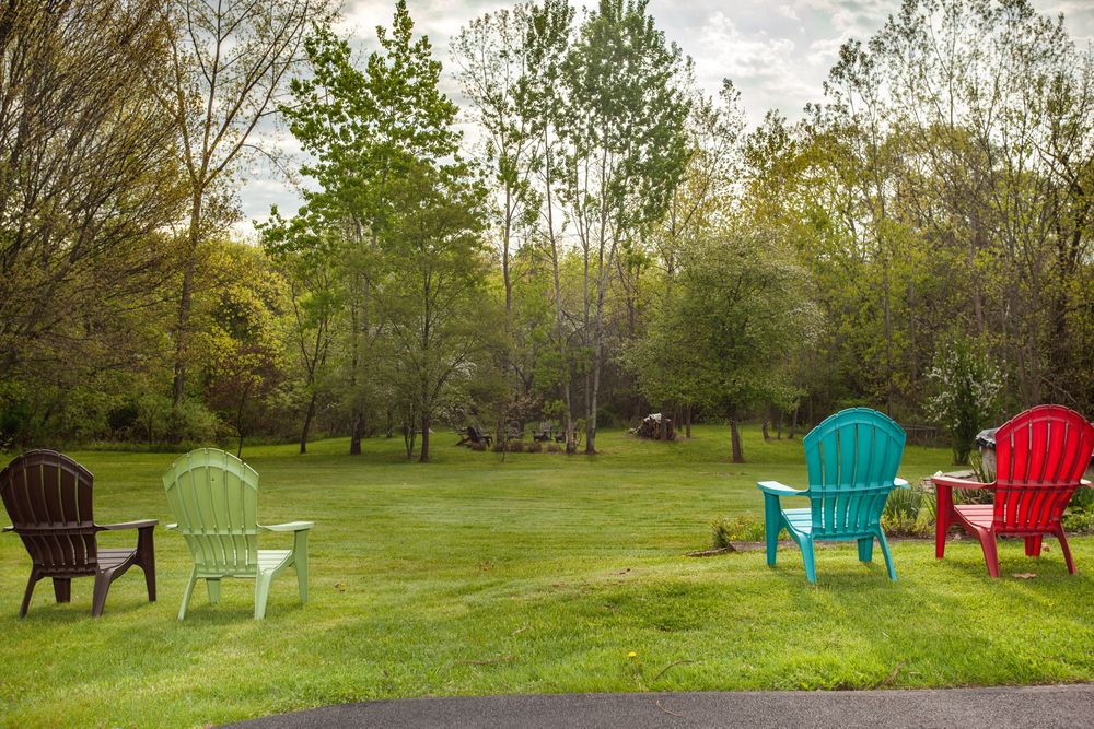 Expansive backyard with colorful Adirondack chairs overlooking a peaceful green landscape.