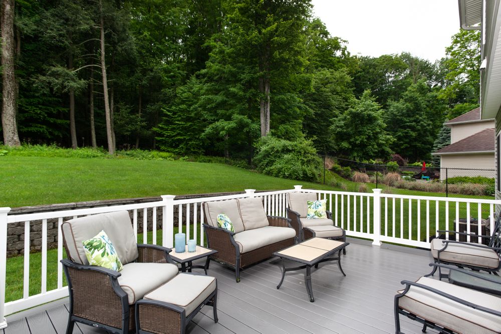 Panoramic view of a spacious deck with comfortable outdoor furniture and lush green surroundings.